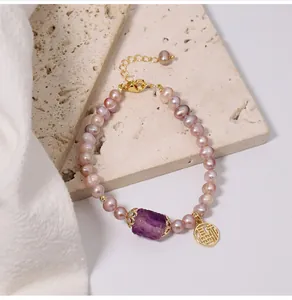 Close-up of purple freshwater pearl bracelet with raw amethyst stone and golden Fu charm
