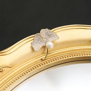 Exquisite macro detail of a ginkgo leaf brooch featuring pave zirconia and a pearl