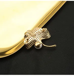 Detailed view of the back of a gold ginkgo leaf brooch featuring a single white pearl