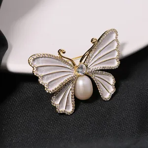 Macro detailweergave van een elegante vlinderbroche met parel en ingelegde schelpvleugels.