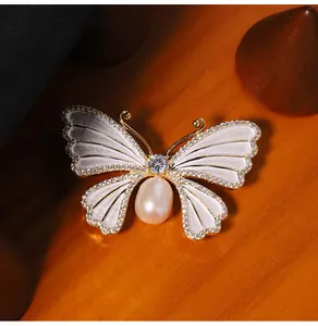 Detailopname van een elegante vlinderbroche met parelmoer en zoetwaterparel design.