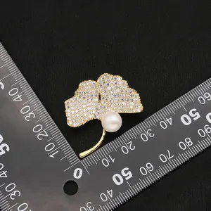 Elegant gold-tone ginkgo leaf brooch with white crystals and a round freshwater pearl