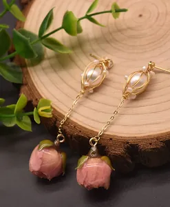 Dettaglio di orecchini in argento 925 con perle e boccioli di rosa rosa conservati