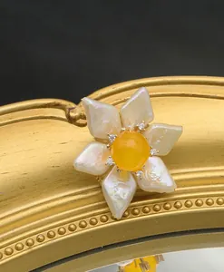 Close-up of handmade baroque pearl sun flower brooch with yellow jade center