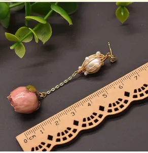 Vista dettagliata di orecchini pendenti con perla e rosa con un righello in legno