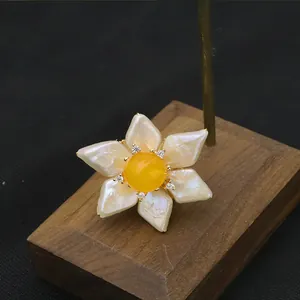Macro view of a vintage sunflower brooch with baroque pearl petals and yellow jade.