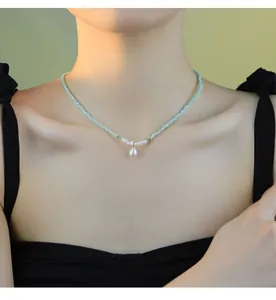 Détail d'un collier artisanal avec pendentif en perle naturelle et perles de verre vertes