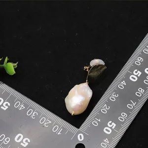 Dettaglio della clip per orecchio in perla barocca con righello per la misura.