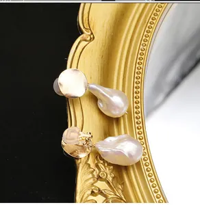 Dettaglio ravvicinato di orecchini di perle naturali barocche su cornice di specchio dorata