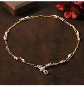 Verfijnd detail van een dubbellaagse gouden ketting met natuurparels voor bril of als ketting.