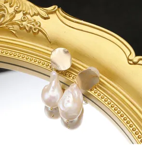 Dettaglio ravvicinato di orecchini con perle barocche e borchie dorate vintage