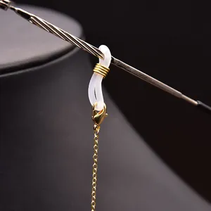 Detailed view of a golden metal glasses chain with white silicone loop connector