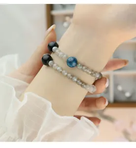 Vista detallada de pulseras en capas de cianita azul natural y piedra de luna gris en la muñeca