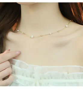 Close-up detail of delicate freshwater pearl and gold bead necklace on model's neck