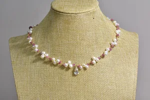 Close-up of a handmade pearl and pink tourmaline necklace with a clear teardrop pendant