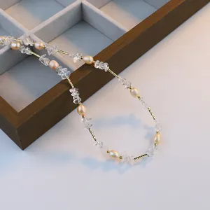 Collier élégant avec cristaux blancs et perles naturelles sur présentoir en bois.