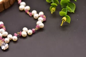 Macro view of handmade necklace with white freshwater pearls and pink tourmaline stones.