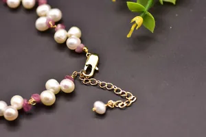 Close-up of gold-plated lobster clasp and extender chain on pearl and tourmaline necklace