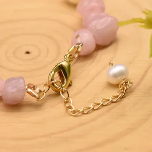 Close-up of gold lobster clasp and white pearl detail on pink crystal bracelet