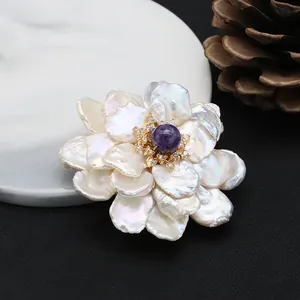 Close-up of luxury baroque natural pearl flower brooch with purple gemstone center