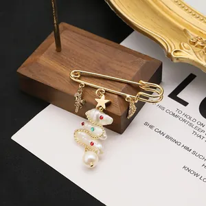 Detail of a Christmas tree brooch with natural freshwater pearls and golden charms.
