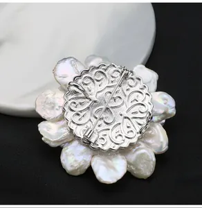 Macro view showing the intricate silver filigree backplate of a baroque pearl flower brooch