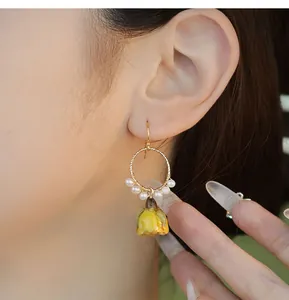 Détail en gros plan de boucles d'oreilles pendantes en résine rose jaune et perles
