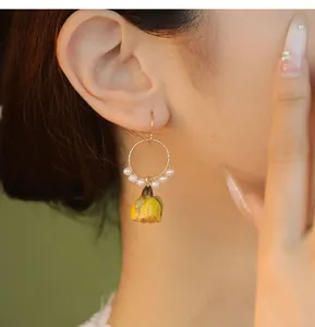Vue détaillée d'une boucle d'oreille rose jaune faite à la main avec perles naturelles