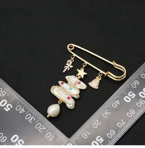 Close-up of a gold Christmas tree brooch featuring natural pearls and festive charms
