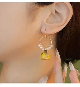 Vue détaillée d'une boucle d'oreille rose en résine faite à la main avec perles