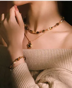 Detalle de un elegante conjunto de collar y pulsera de perlas naturales y ojo de tigre.