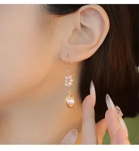 Detailed close-up view of handmade 18K gold-plated natural pearl drop earring on model
