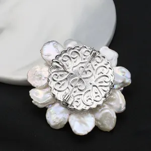 Back view of handmade flower brooch with natural baroque pearls and filigree metal plate.
