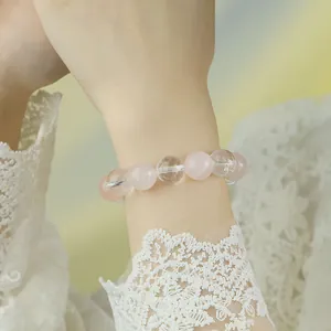 Elegantes Armband aus natürlichem Rosenquarz und Bergkristall am Handgelenk einer Frau.