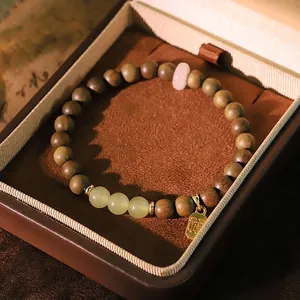 Vintage green sandalwood and Hetian jade bracelet presented in an elegant brown jewelry gift box