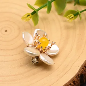 Detailweergave van barokke parel bloemspeld met geel midden en kristallen accenten