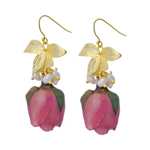 Élégantes boucles d'oreilles pendantes rose avec perles naturelles et détails de nœud doré