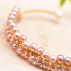 Macro detail of handmade pink freshwater pearl bracelet featuring intricate gold wire wrapping