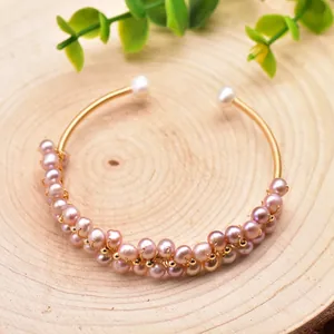 Detailed macro view of pink freshwater pearls hand-wrapped on a golden elastic bracelet.