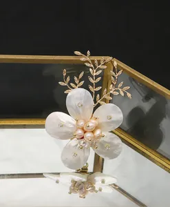 Vista macro de un elegante broche floral con perlas naturales y pétalos de nácar tallados.