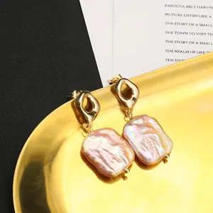 Detailed close-up of Baroque pearl earrings with gold hollow diamond-shaped studs on a tray.