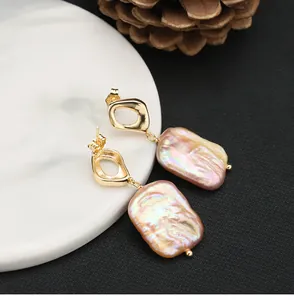 Macro view of unique natural baroque pearl earrings with geometric gold-toned tops