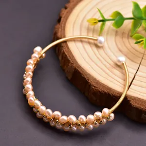 Detailed macro view of handmade gold wire-wrapped natural freshwater pearl stretch bangle