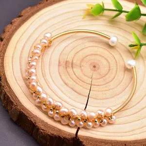 Detailed view of handmade freshwater pearl bracelet with intricate gold wire wrapping.