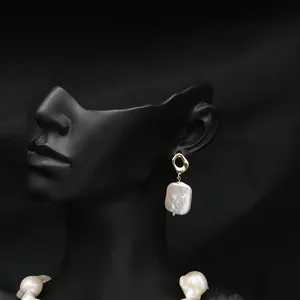Natural baroque pearl drop earrings with gold hollow geometric stud on black mannequin