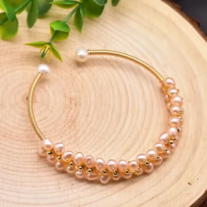 Close-up of a handmade wire-wrapped bracelet featuring natural pink freshwater pearls.