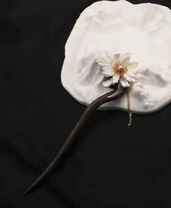 Gedetailleerd aanzicht van een ebbenhouten haarstokje met parelbloem en gouden kwast