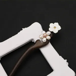 Gros plan d'un élégant pic à cheveux en ébène avec perles et fleur en nacre sculptée