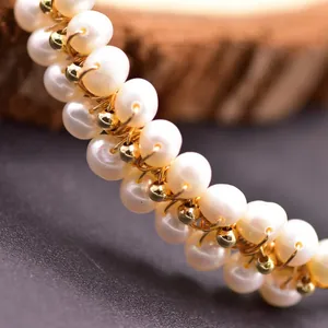 Macro detail of handcrafted freshwater pearl bracelet with gold wire wrapping texture.