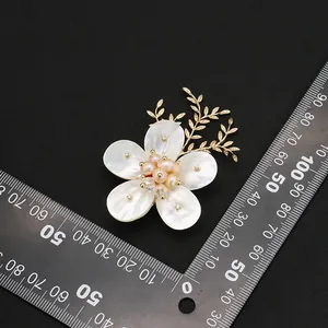 Broche de flor de camelia de nácar natural con perlas y hojas doradas